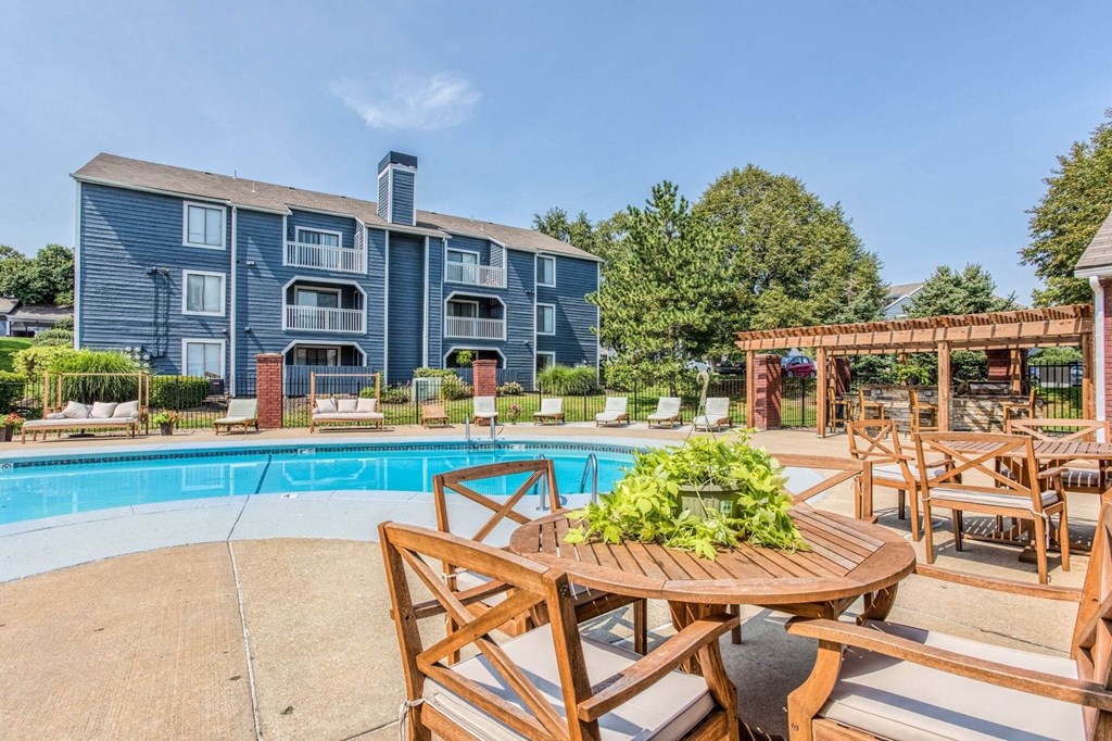 A poolside table with chairs and a building in the background.