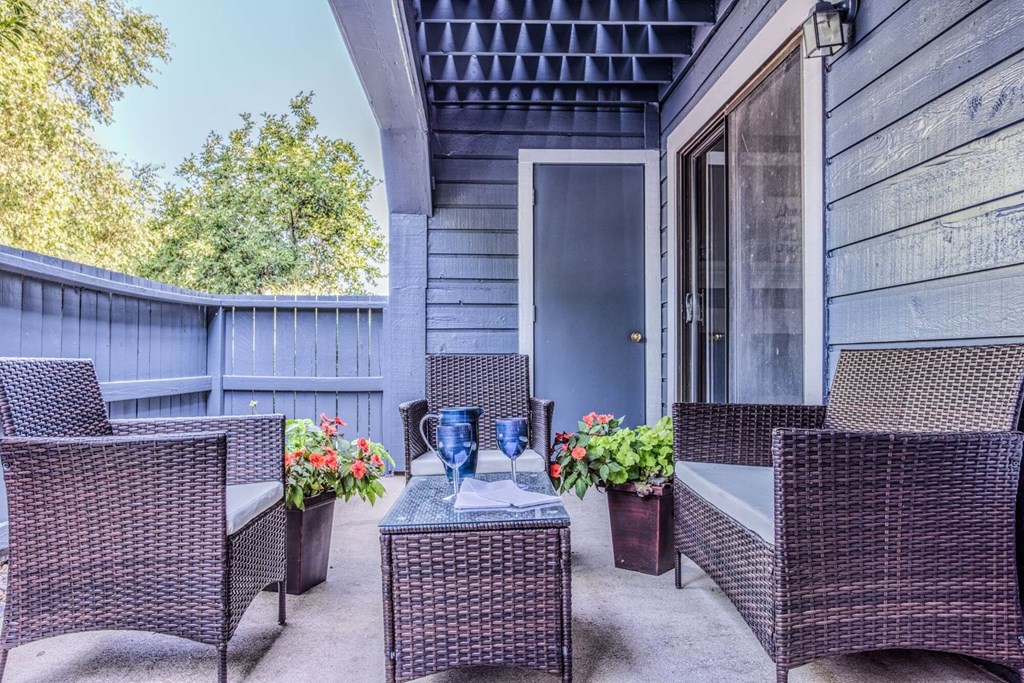 A patio with a table and chairs and a vase of flowers.