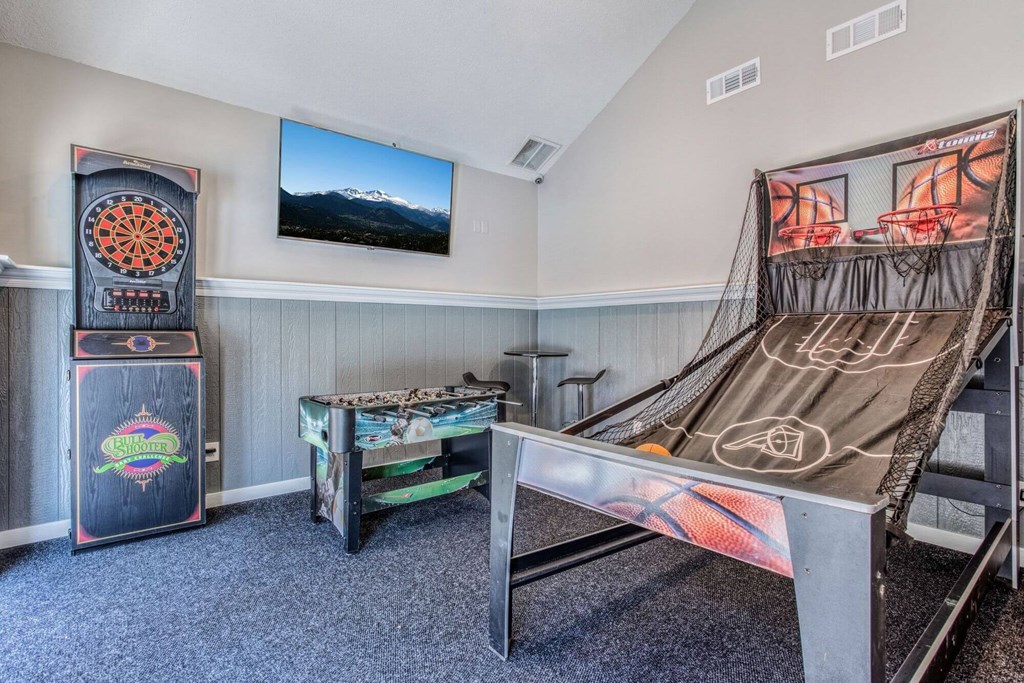 A room with a miniature golf table and an arcade game.