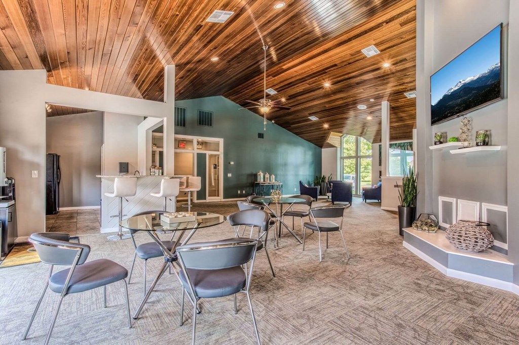 A modern living room with a wooden ceiling and a large flat screen TV mounted on the wall.