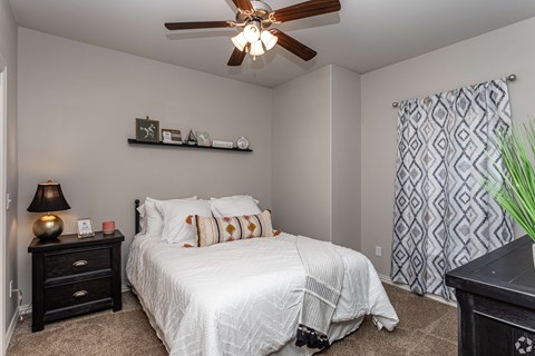 A bedroom with a white bed and a ceiling fan.