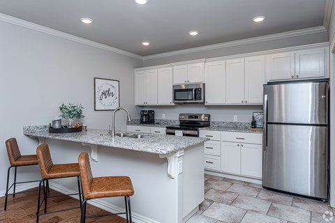 A kitchen with white cabinets and a stainless steel refrigerator.