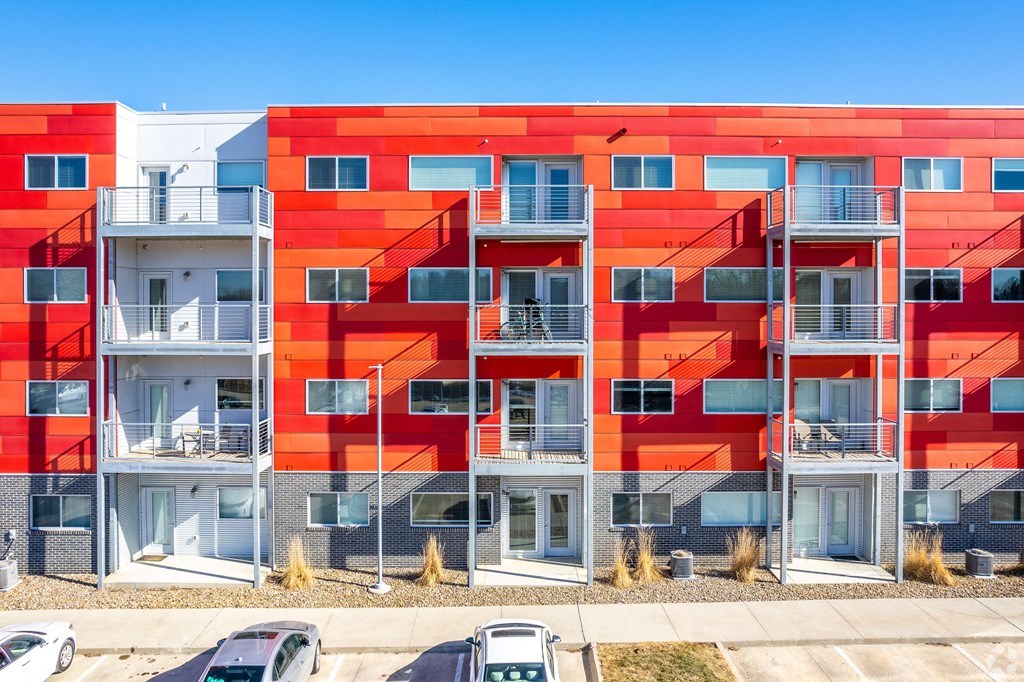 a red apartment building with balconies and cars in front of it
