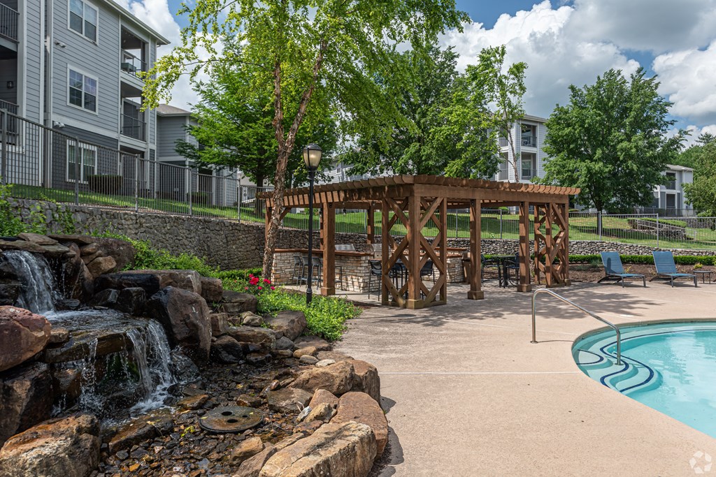 an outdoor patio with a waterfall and a wooden gazebo