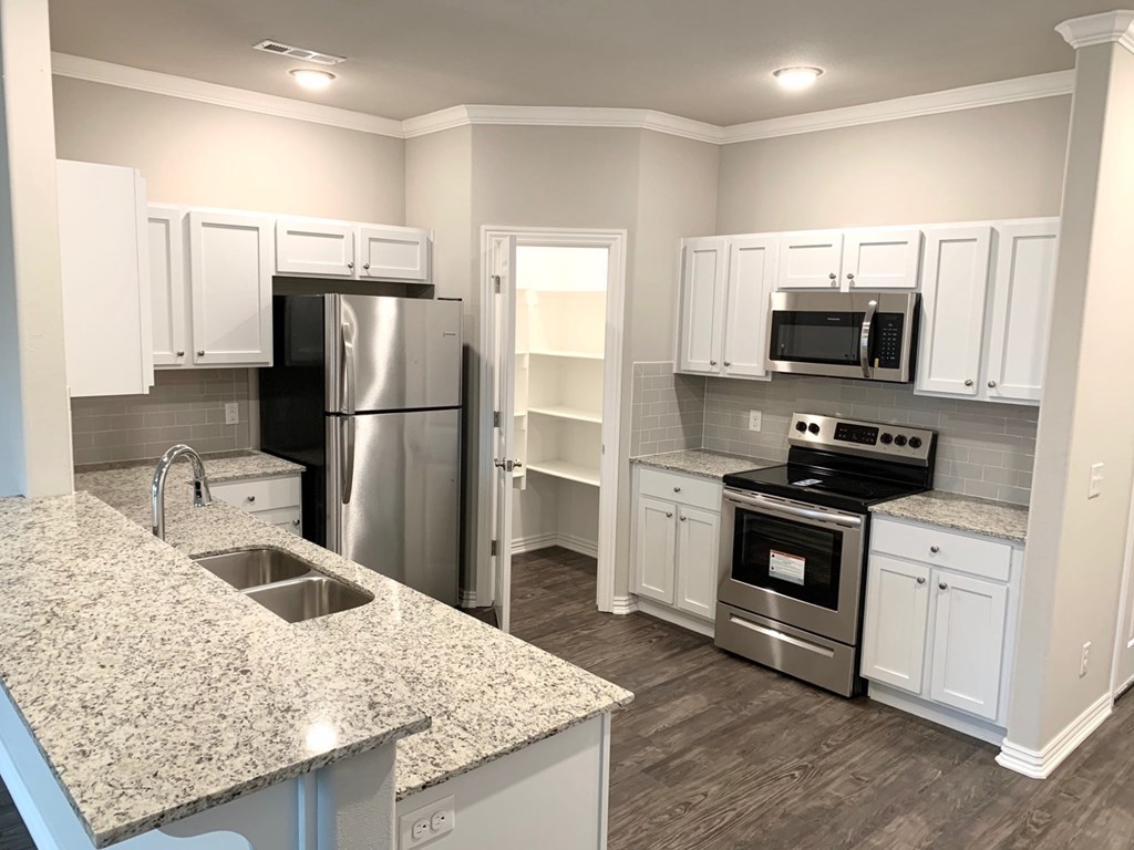 a kitchen with white cabinets and a granite counter top