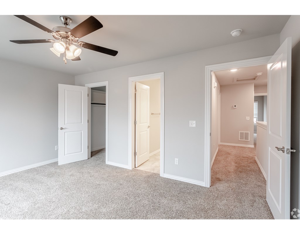 a bedroom with two doors and a ceiling fan