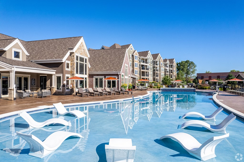 a large swimming pool with white chairs in front of apartment buildings  at Waterside Residences on Quivira, Lenexa, Kansas