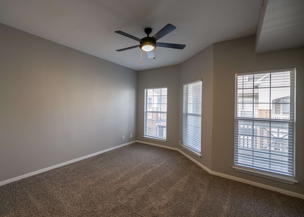 an empty living room with a ceiling fan and three windows at Centennial Park Apartments, Kansas, 66213
