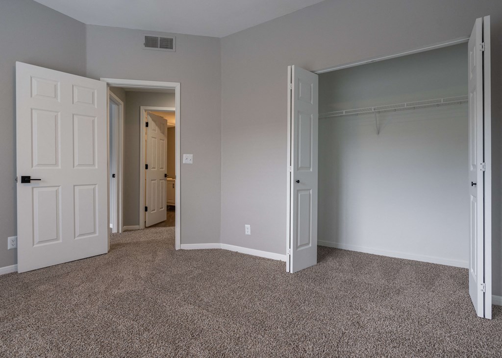 an empty bedroom with two doors and a closet an empty bedroom with two doors and a closet at Centennial Park Apartments, Overland Park