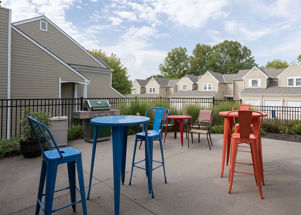 a patio with colorful chairs and tables and houses in the background at Centennial Park Apartments, Overland Park, 66213