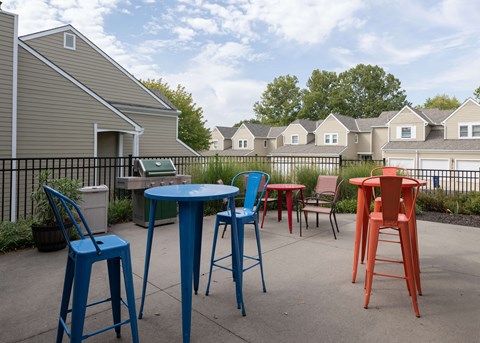 a patio with colorful chairs and tables and houses in the background at Centennial Park Apartments, Overland Park, 66213