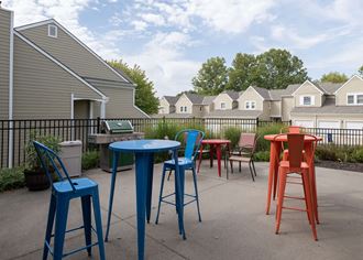 a patio with colorful chairs and tables and houses in the background