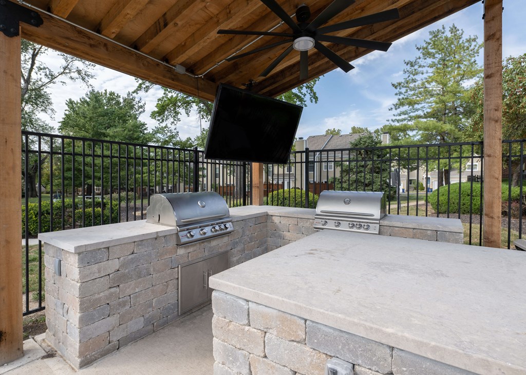 a stone outdoor entertaining area with a stone grill and a tv at Centennial Park Apartments, Kansas, 66213