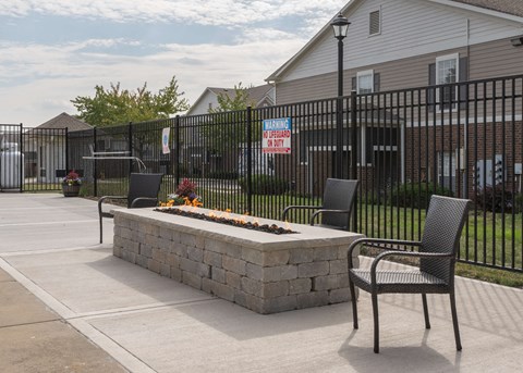 a fire pit with two chairs in front of a fence at Centennial Park Apartments, Overland Park
