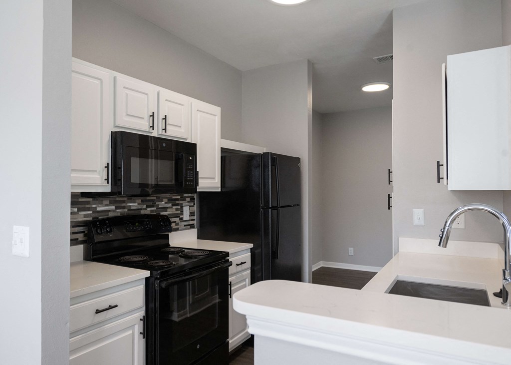 a kitchen with black appliances and white cabinets and a sink at Centennial Park Apartments, Overland Park, 66213