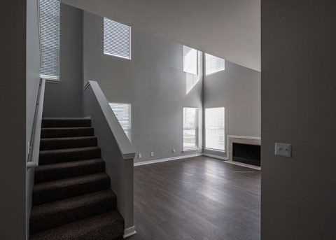 an empty living room with stairs and a fireplace at Centennial Park Apartments, Overland Park