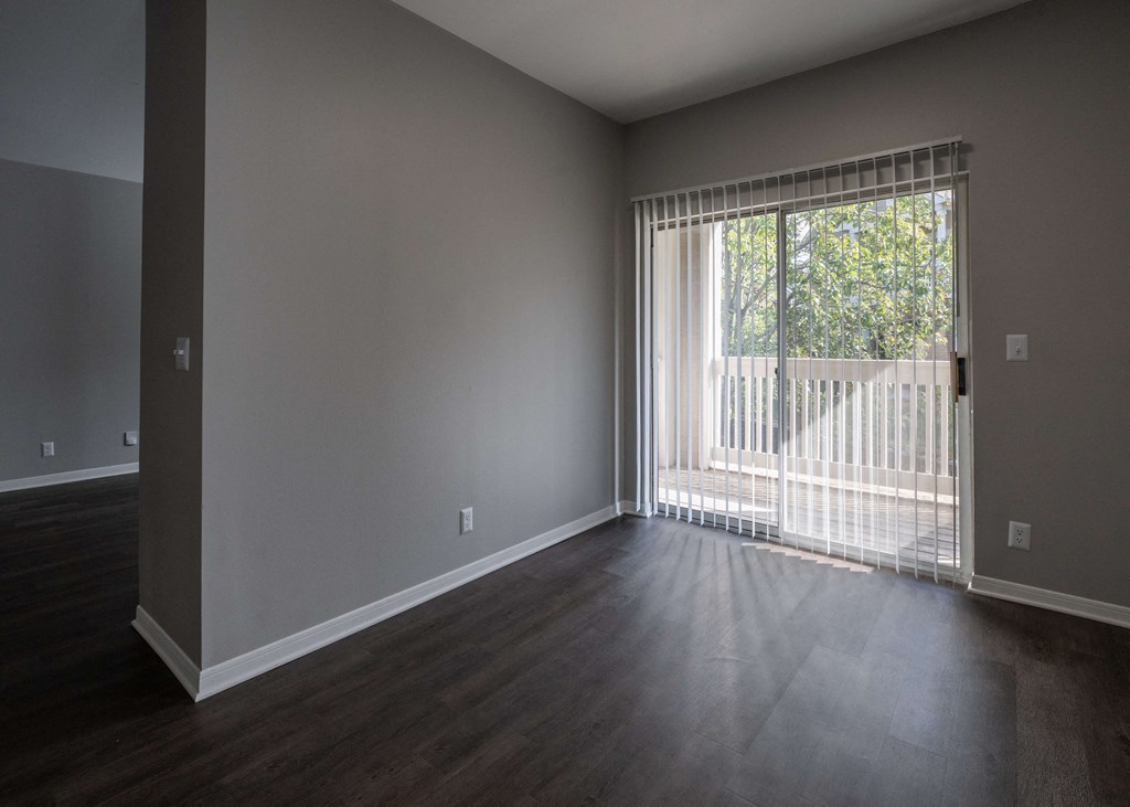 an empty living room with a large window and wood floors at Centennial Park Apartments, Overland Park, Kansas