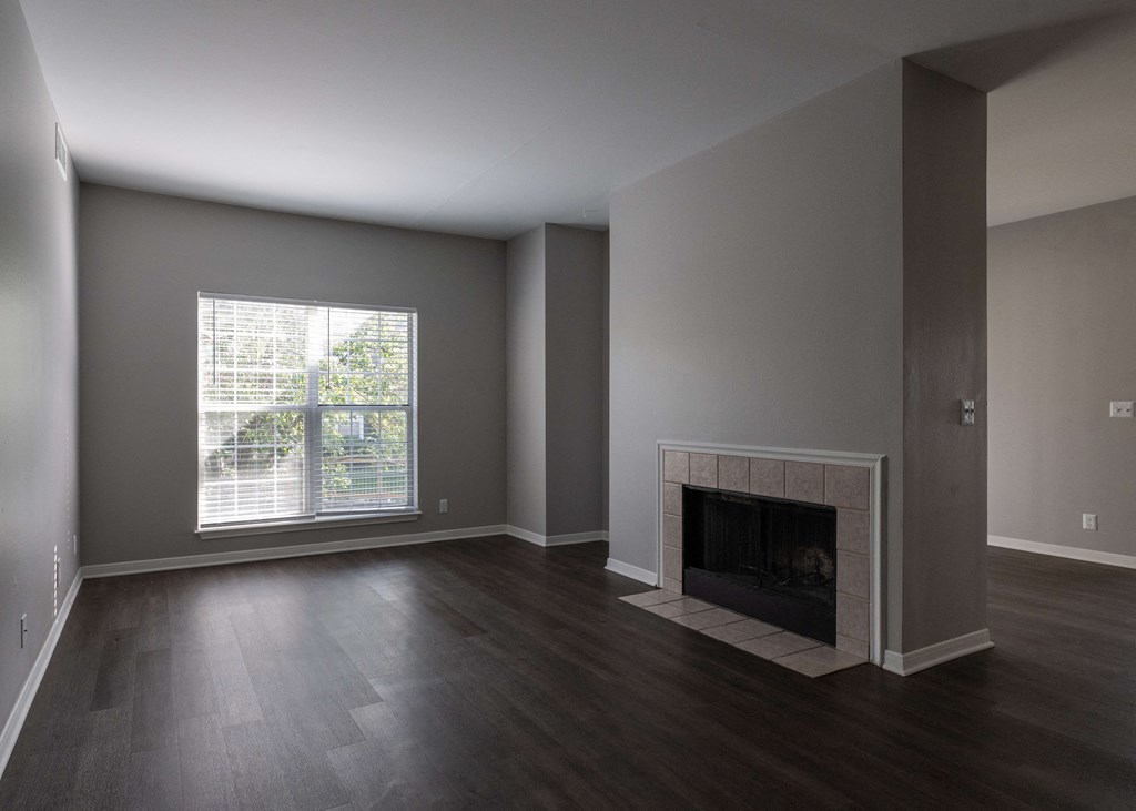 an empty living room with a fireplace and a window at Centennial Park Apartments, Overland Park