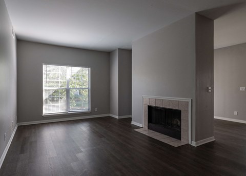 an empty living room with a fireplace and a window at Centennial Park Apartments, Overland Park