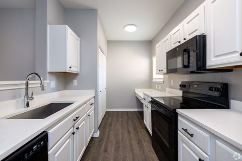 A kitchen with white cabinets and black appliances.