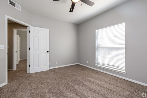 A room with a carpeted floor and a ceiling fan.