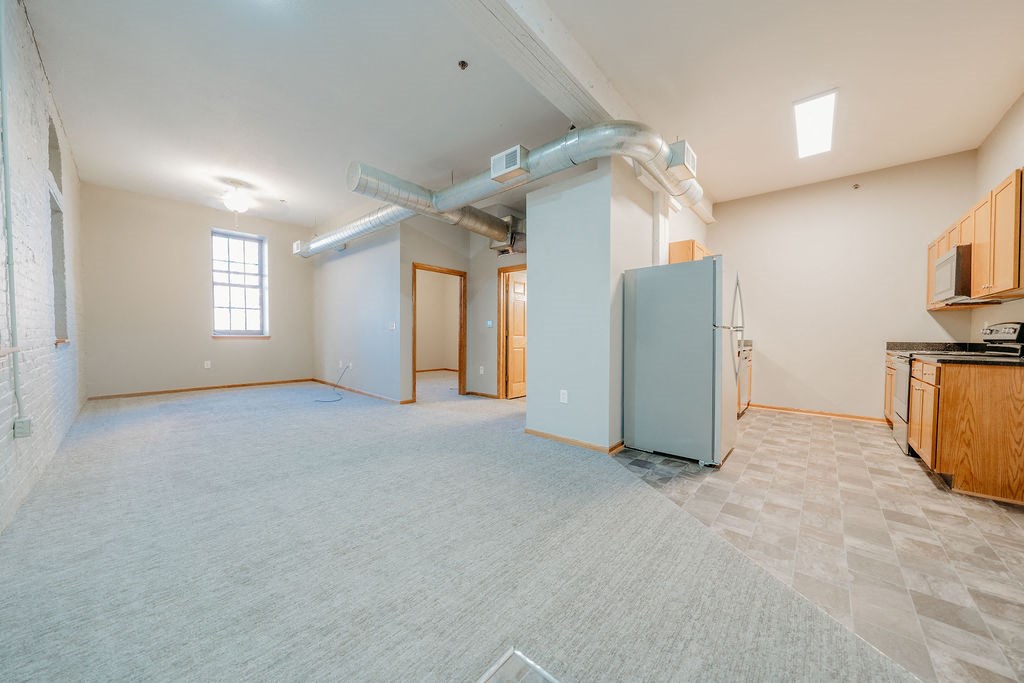 an empty room with a kitchen and a refrigerator