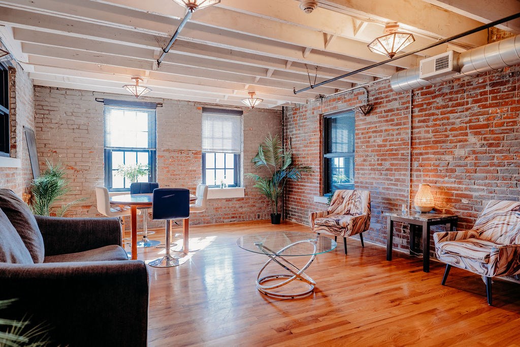 a living room with exposed brick walls and a wood floor