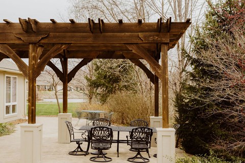 a wooden pergola with a table and chairs under it