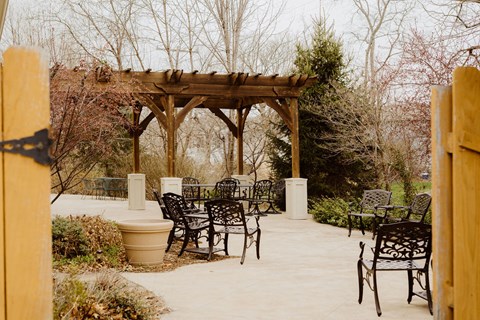 a backyard patio with a wooden pergola and chairs