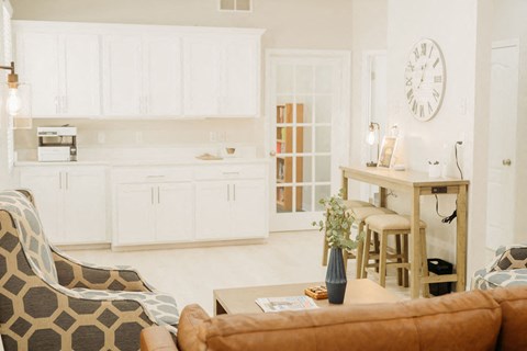 a living room and kitchen with a large clock on the wall