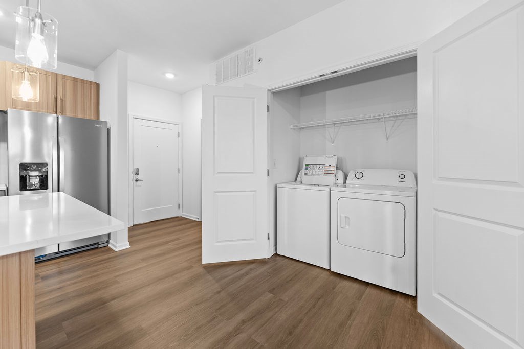 A modern kitchen with a refrigerator, oven, and washing machine.