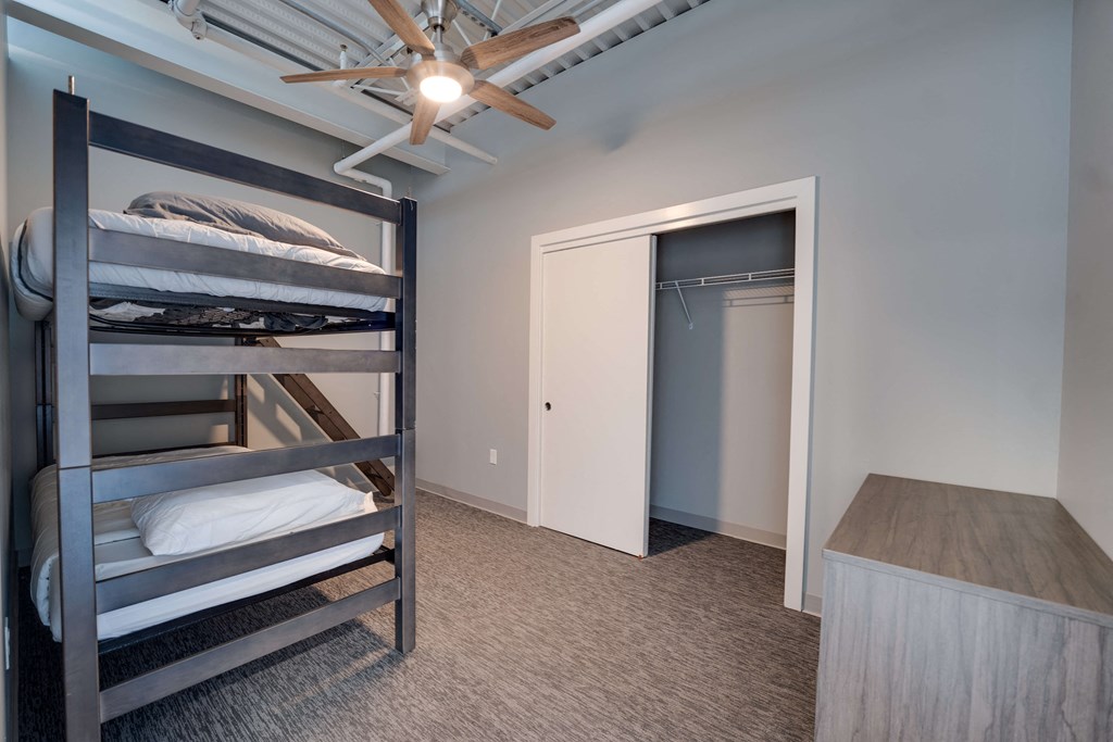 a bedroom with bunk beds and a closet and a ceiling fan