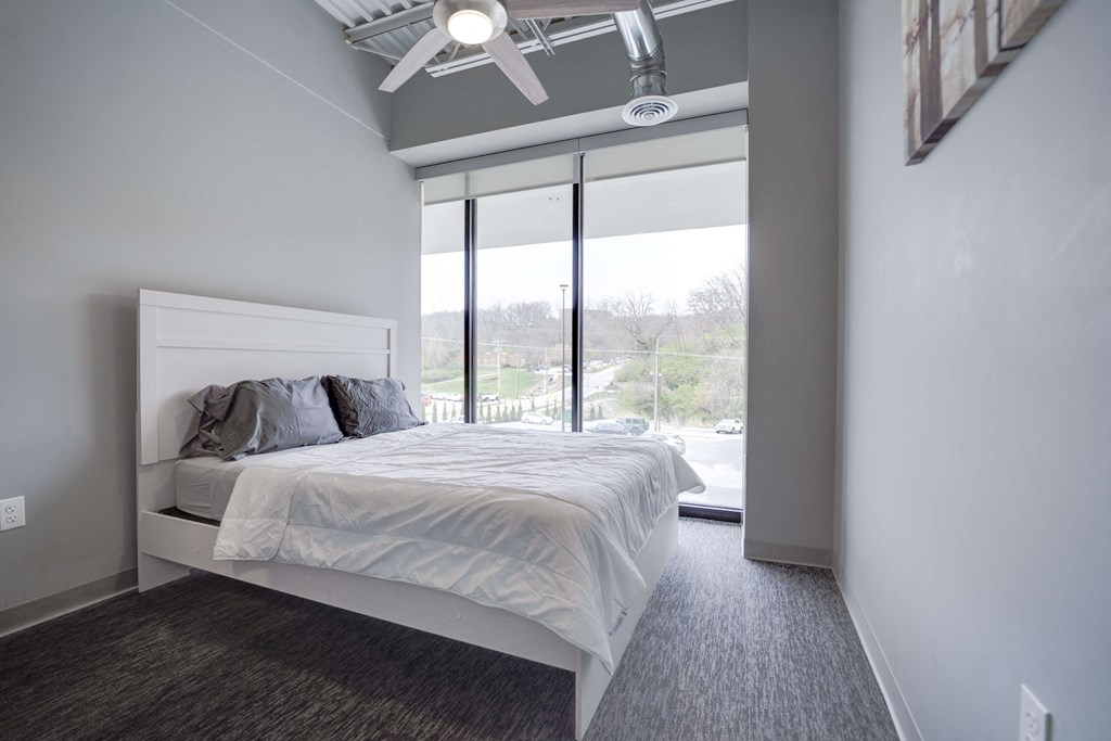 a bedroom with a white bed and a large window
