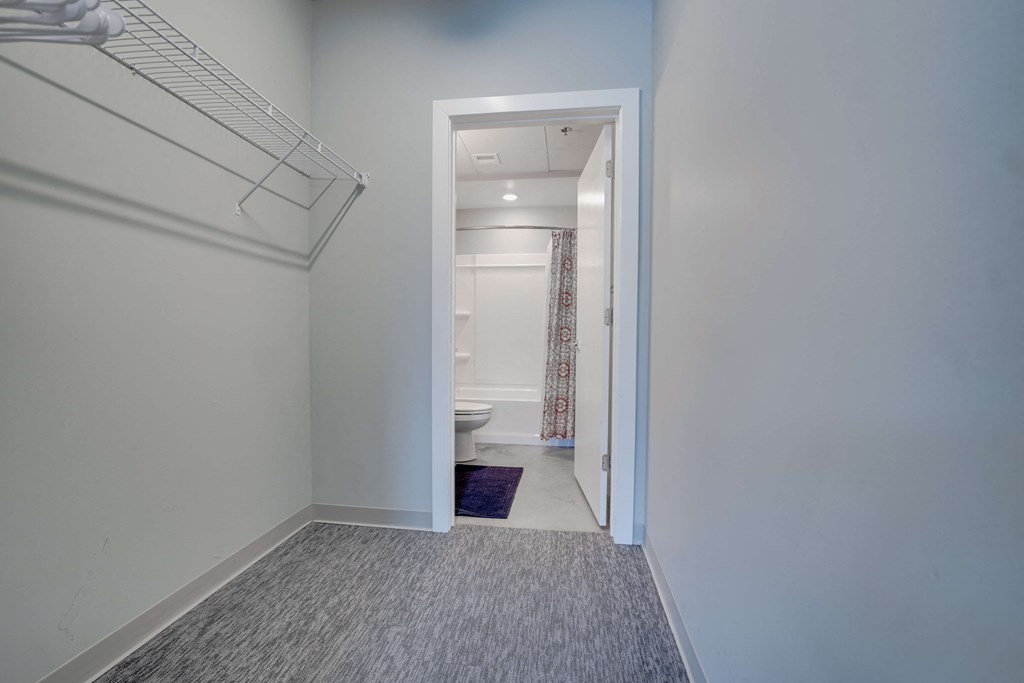 a long hallway with a door to a bathroom and a hallway mirror with a closet