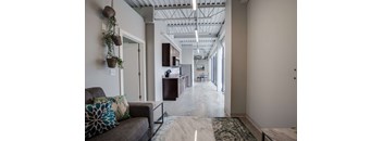 a long hallway with a couch and a kitchen in a building
