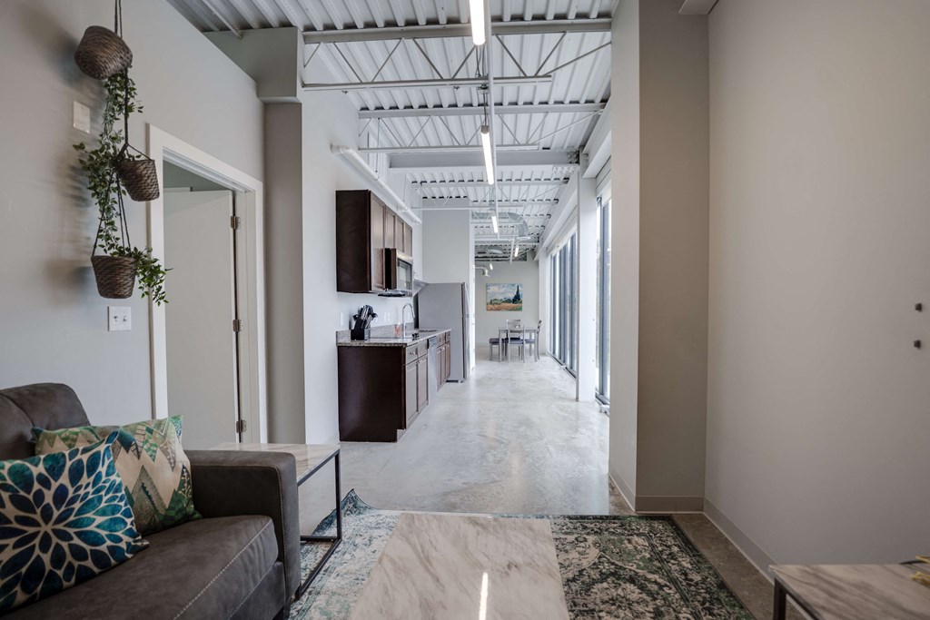 a long hallway with a couch and a kitchen in a building