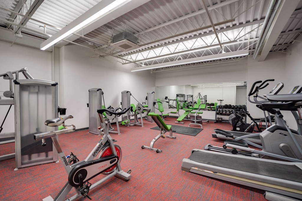 a gym with cardio equipment and weights on the floor