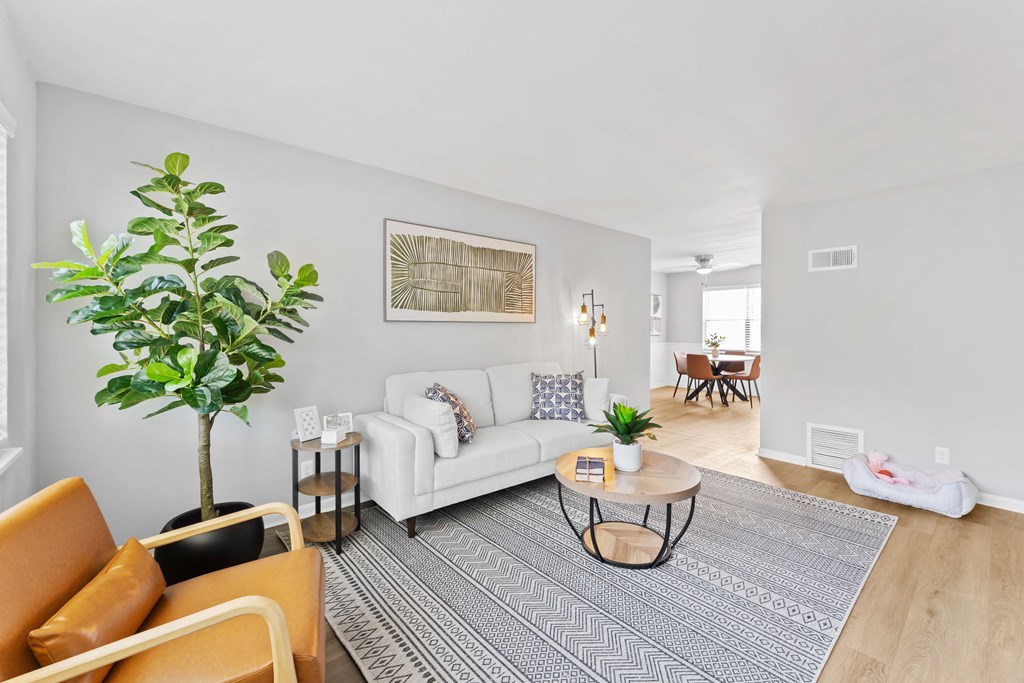 A living room with a white couch, a coffee table, and a potted plant.