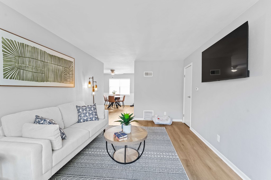 A living room with a white couch and a large painting on the wall.