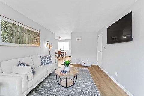 A living room with a white couch and a large painting on the wall.
