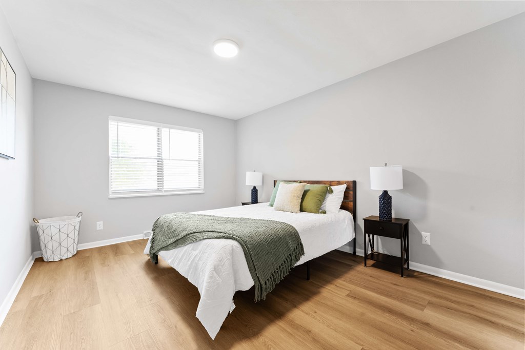 A bedroom with a bed, nightstand, and window.