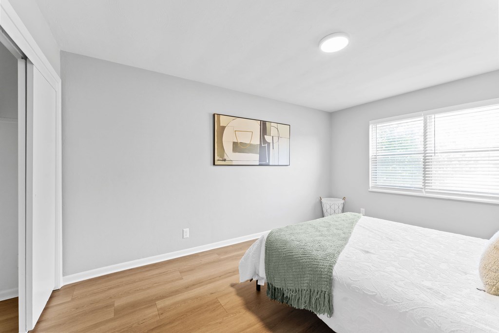 A bedroom with a bed, a nightstand, and a painting on the wall.