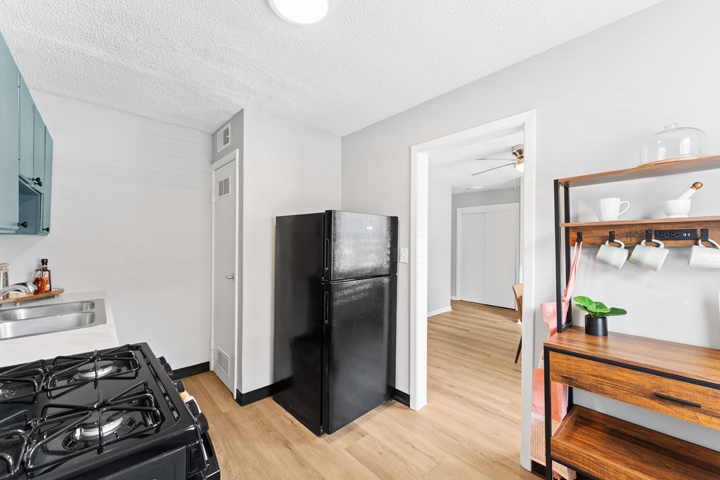 A black refrigerator sits in a kitchen next to a stove.