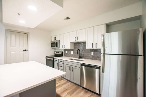 A kitchen with a white counter top and stainless steel appliances.