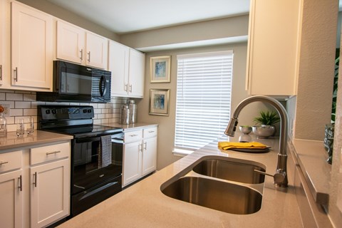 A kitchen with a black stove top oven and a black microwave.