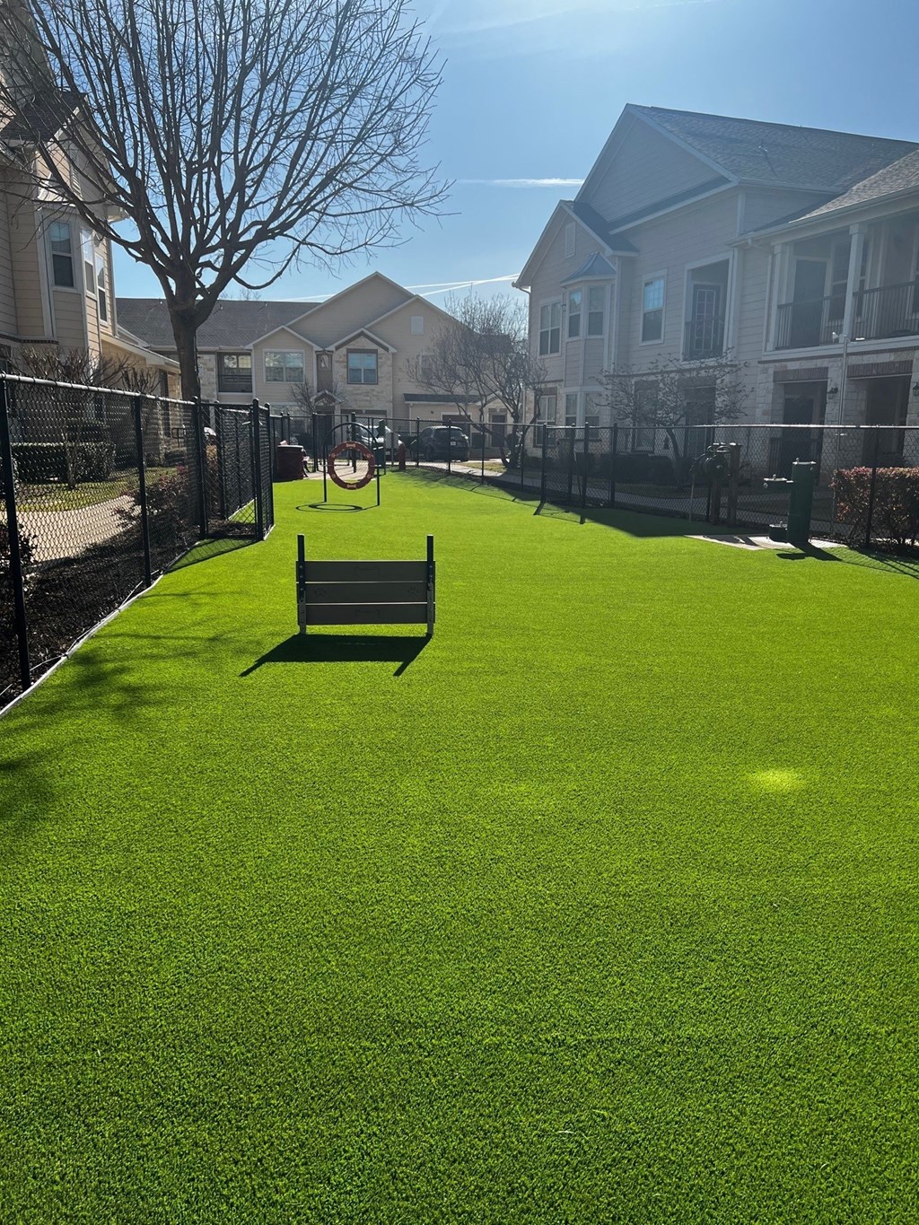 a park bench in the middle of a grassy area with houses in the background