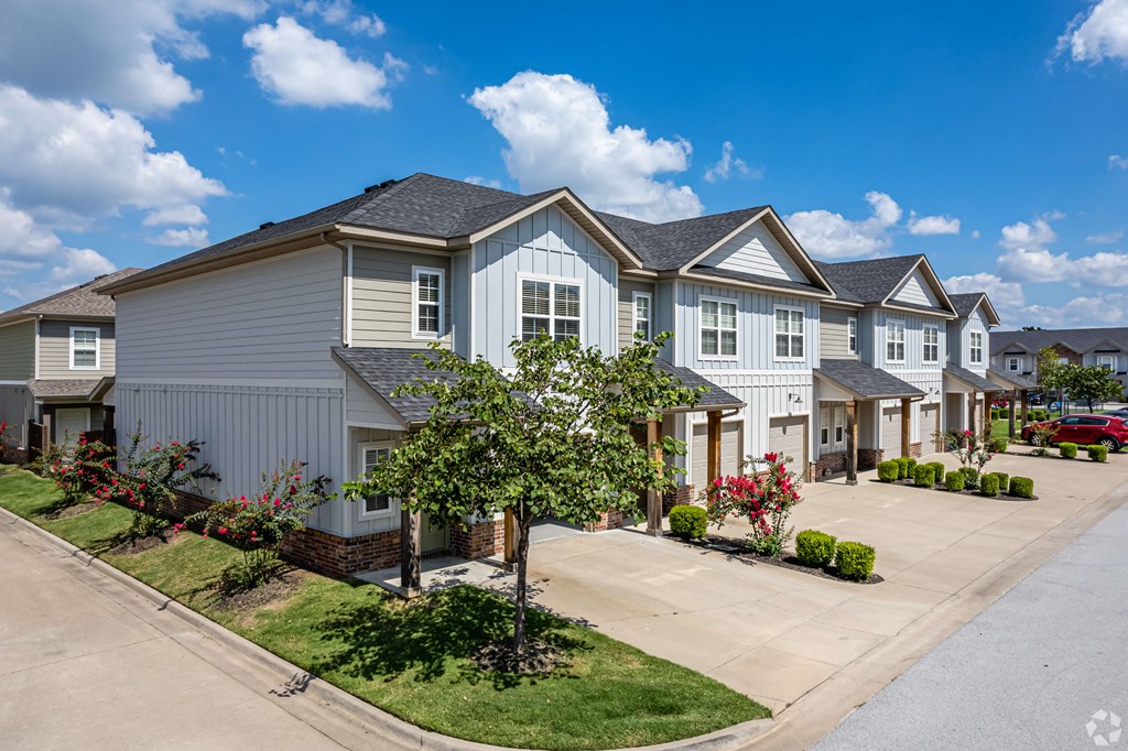 a row of townhomes on a street with lawns and trees