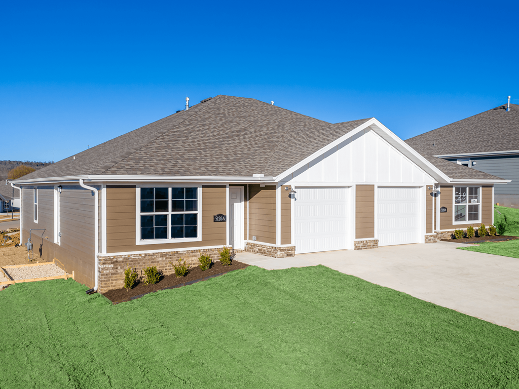 the front of a home with a green lawn and a blue sky