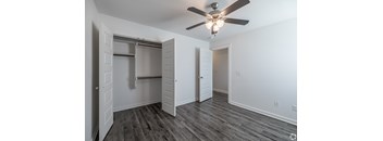 A room with a ceiling fan and a closet with a sliding door.
