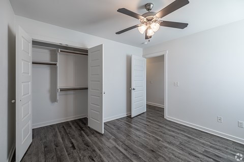 A room with a ceiling fan and a closet with a sliding door.